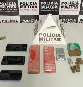 02 barras de substância de origem vegetal semelhante à maconha, além de 01 barra menor e algumas pequenas porções do mesmo entorpecente. em cima da mesa de registro de materiais apreendidos da PM