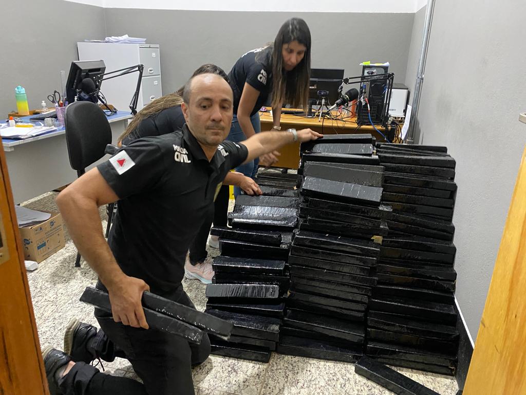 Policiais Civis empilhando tablets de maconha.